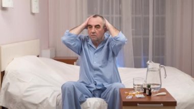 Pijama yatağa haplarla kase gece masada oturan yaşlı adam depresif