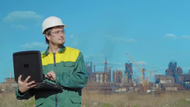 The male engineer projects the work. Sunny day and clouds. The man is dressed in a green sunglass vest — Stock Video