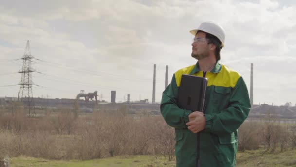 O engenheiro masculino projeta o trabalho. Dia ensolarado e nuvens. O homem está vestido com um colete de vidro verde — Vídeo de Stock