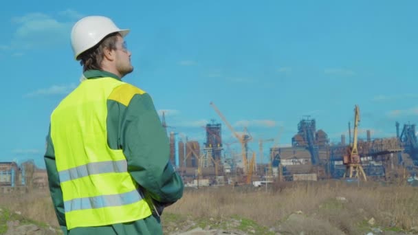 The male engineer projects the work. Sunny day and clouds. The man is dressed in a green sunglass vest — Stock Video