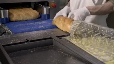 Bir somun ekmek parçalar halinde kesme ve torba ambalaj. Makine kesme ekmek için. Dilimlenmiş ekmek fabrikası. Üretim süreci. Ekmek dilimi otomatik makine.