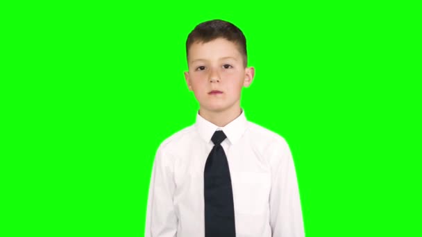 Маленький мальчик, стоящий в студии перед зеленым фоном, демонстрирует разные эмоции. Съемка на зеленом экране . — стоковое видео