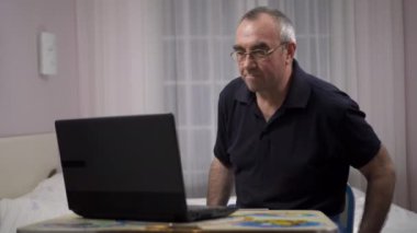 Dizüstü bilgisayar kullanarak yaşlı gri saçlı erkek, bir dizüstü bilgisayar üzerinde futbol izlerken ve üzgün alır