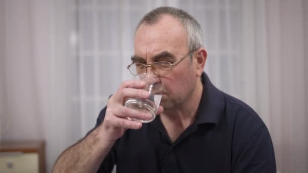 Пожилой человек пьет воду, эмоции недовольства и раздражения — стоковое видео