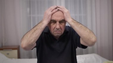 Baş ağrısı olan yaşlı adam. Yaş ile ilgili sağlık sorunları