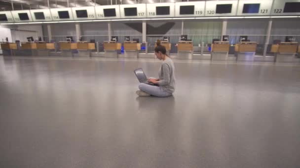 Mujer trabaja en el ordenador portátil y esperando el vuelo en el aeropuerto en la terminal en el suelo . — Vídeos de Stock