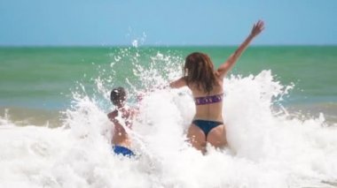 anne ve oğlu dalgalar üzerinde denize atlamak, sevin, eğlenmek.