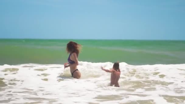 Mutter und Sohn springen auf den Wellen ins Meer, freuen sich, haben Spaß. — Stockvideo