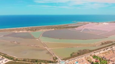 Kıyı tuz bataklıkları ile çok renkli tuz gölleri, havadan görünümü, drone ile video çekim. Pembe tuz gölleri ve turkuaz deniz, hava video.