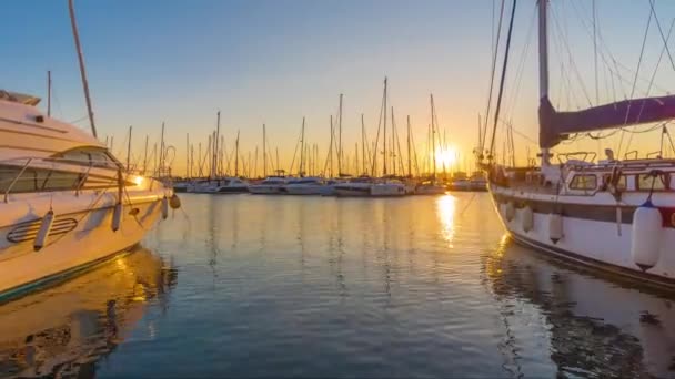 Zaman Atlamalı. Rıhtıma bağlı yatlar ile marinada gün batımı sahnesi, durgun suya yansıyan güneş ve gökyüzü güzel rengi. — Stok video