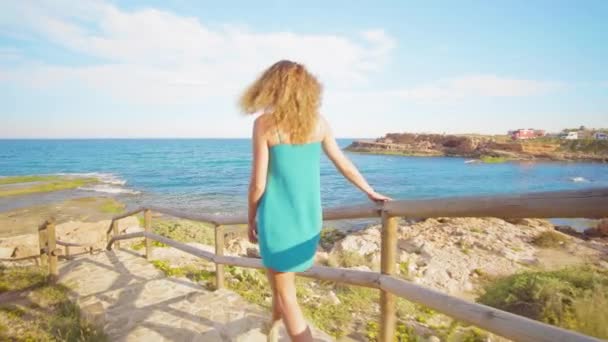 Achteraanzicht van een vrouw lopen naar de zee op de mooie trappen. — Stockvideo