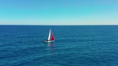 Güneşli bir günde açık denizde yelken açmak. Kırmızı yelkenli yelkenli.