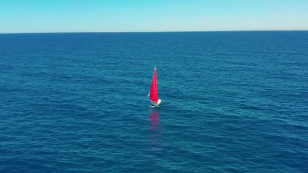 A jacht a nyílt tengeren vitorlázik napsütésben. Vitorlás hajó piros vitorlával. — Stock videók
