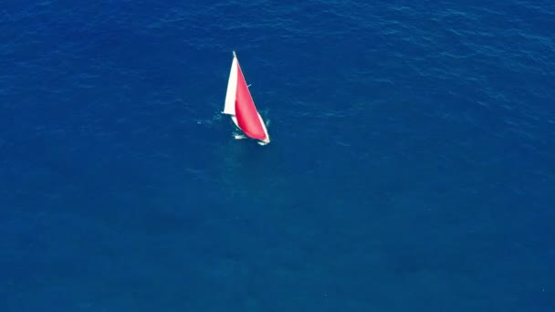 Flygvy. Segelbåt med röd segel i öppet hav. — Stockvideo