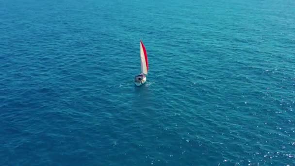 Luchtfoto. Zeiljacht met rood zeil in de open zee. — Stockvideo