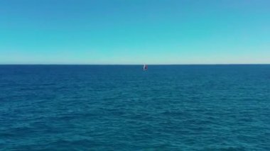 Havadan görünüm. Kırmızı yelkenli güzel yelkenli yat güneşli bir günde zümrüt denizde yelken açıyor.