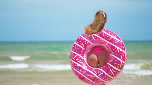 Skinkor flickor dansar med rosa donut. flicka i rosa bicini på stranden. Vacker sexig kvinna. — Stockvideo