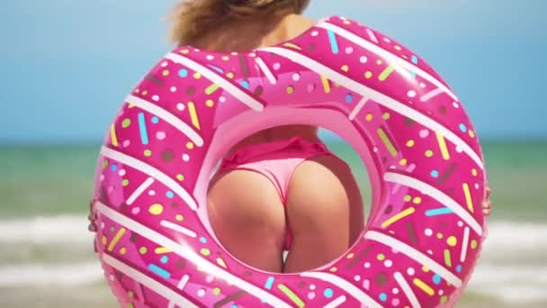 엉덩이 여자 핑크 도넛으로 춤. 해변에서 분홍색 비키니소녀. 아름다운 섹시한 여자. — 비디오