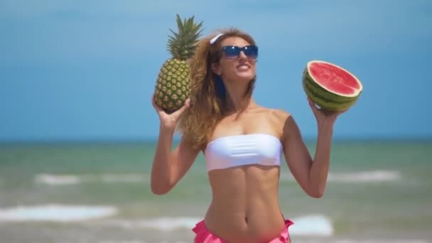 年轻美丽的女孩在海滩边与热带水果共舞，玩得很开心。 概念快乐与健康食品. — 图库视频影像
