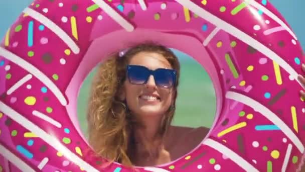 Schönes Mädchen mit aufblasbarem Donut, das gegen das Meer tanzt. Nahaufnahme. — Stockvideo