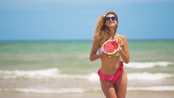 Tančící dívka s polovinou šťavnatého melounu na pozadí nádherného moře. — Stock video