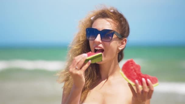 Mujer sonriente comiendo sandía en la playa. Mujer comiendo sabrosas frutas de verano. Feliz verano. . — Vídeos de Stock