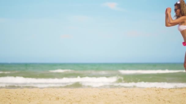 A girl in a bathing suit plays sports against the backdrop of the sea. Effective exercises for the buttocks. — Stock Video