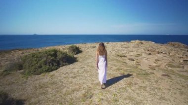 Havadan görünüm. Beyaz elbiseli bir kız denizin kenarına gider..
