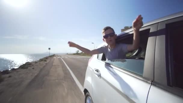 Boy looking out the car window and waving his hand. — Stock Video