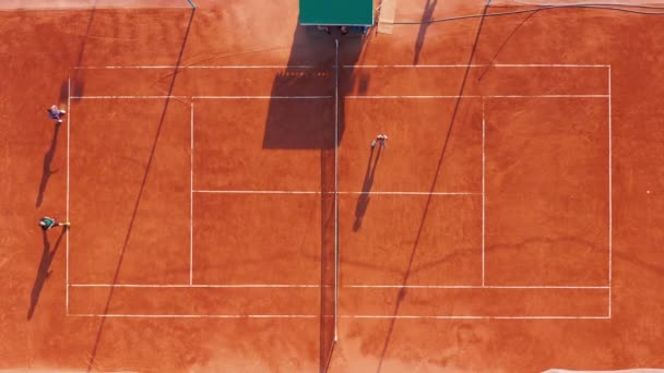 Vista aérea. Los jugadores están jugando tenis en la cancha naranja. — Vídeo de stock