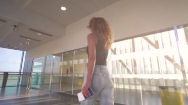 Kız hava ovasına gidiyor, havaalanındaki terminale gidiyor, elinde pasaport ve bilet var..