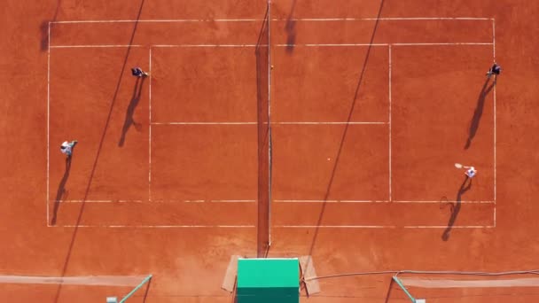 Vista aérea. Los jugadores están jugando tenis en la cancha naranja. — Vídeo de stock