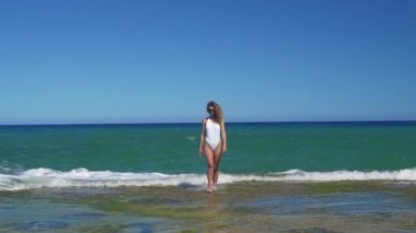 Deniz kıyısında bikinili genç kadın ve su dalgaları hava manzara sıçrayan. Kayalık deniz plaj drone görünümünde güzel kadın.