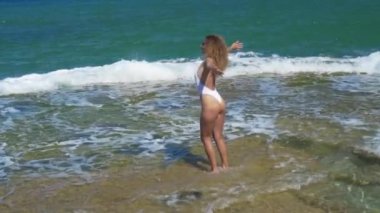 Havadan görünüm. Kayalık deniz plajında dans eden ince kadın.