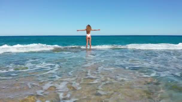 Sexy Girl de pie en el acantilado en la playa rocosa. Una mujer mira a la distancia . — Vídeos de Stock