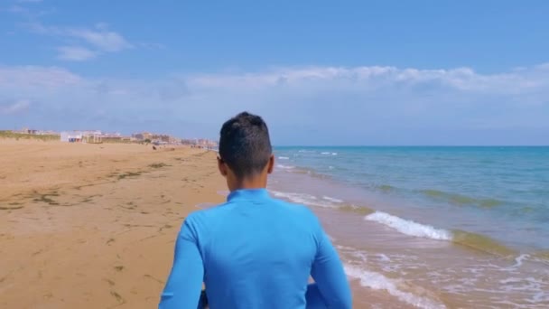 Atletisk kille jogging längs kusten på en solig dag. Jogging utomhus nära havet. Koncept hälsosam, aktiv livsstil. — Stockvideo