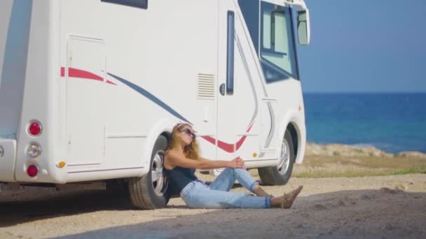 Κορίτσι τουρίστρια κοντά στο τροχόσπιτό της στο πάρκινγκ κοντά στη θάλασσα. — Αρχείο Βίντεο