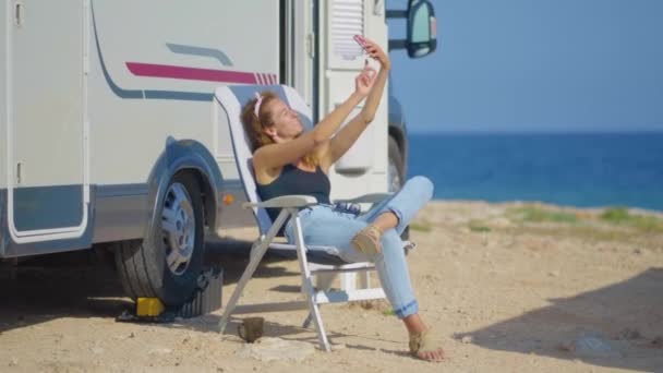 Rapariga a fazer selfie perto da caravana. Viajar mulher por motor móvel casa RV campista van . — Vídeo de Stock