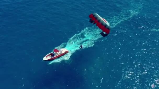 Luchtfoto. Vliegen met parachute achter een boot. Extreme watersport in de zee. Parasailen. — Stockvideo