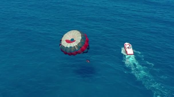 鸟瞰。人们乘坐五颜六色的降落伞，被摩托艇拖着。在蓝天上滑翔. — 图库视频影像