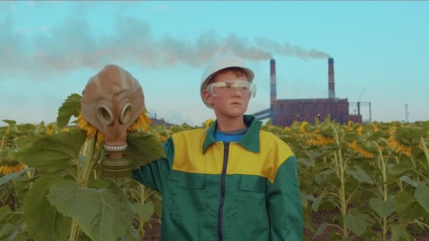 Παιδί σε προστατευτική μάσκα με το φυτό ηλιοτρόπιο στο φόντο βιομηχανικό εργοστάσιο. Περιβαλλοντική ρύπανση, οικολογική καταστροφή. Φροντίδα για τις μελλοντικές γενιές. — Αρχείο Βίντεο