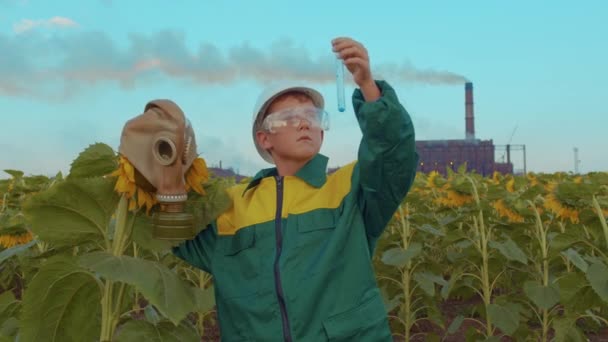 Anak bertopeng pelindung dengan tanaman bunga matahari di pabrik industri latar belakang. Polusi lingkungan, bencana lingkungan. Menjaga generasi mendatang . — Stok Video