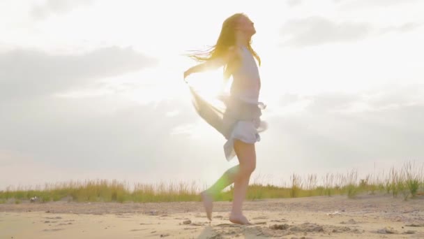 Deniz sahilinde gün batımında dans eden kaygısız kadın. Kız dönüyor. Gün batımında kadınlık. Yavaş çekim. — Stok video