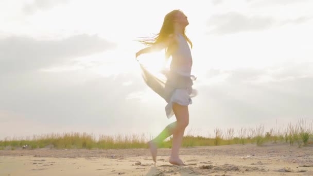 Mulher despreocupada dançando no pôr do sol na praia do mar. Rapariga a girar. A feminilidade ao pôr-do-sol. Movimento lento . — Vídeo de Stock