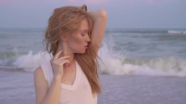 Retrato menina com cabelos vermelhos e olhos azuis olhando para a câmera à beira-mar . — Vídeo de Stock