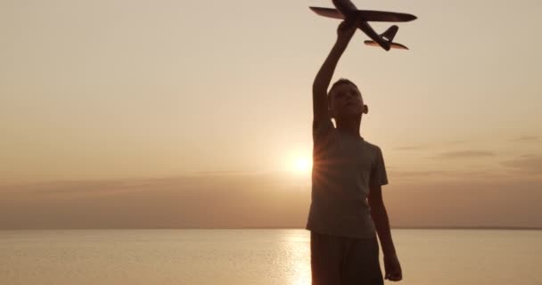 Criança feliz brincando com avião de brinquedo contra o verão de sol laranja. Melhor conceito de infância . — Vídeo de Stock