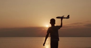 Mutlu çocuk gün batımı arka planda bir oyuncak uçak ile çalışır. Çocukluk hayalleri.