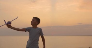 Turuncu güneş yaz karşı oyuncak uçak ile oynayan mutlu çocuk. En iyi çocukluk konsepti.