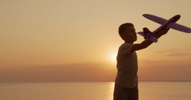 Mutlu çocuk gün batımı arka planda bir oyuncak uçak ile çalışır. Çocukluk hayalleri.