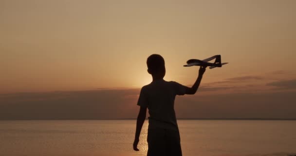 Gelukkig kind loopt met een speelgoed vliegtuig op een zonsondergang achtergrond. Jeugddromen. — Stockvideo